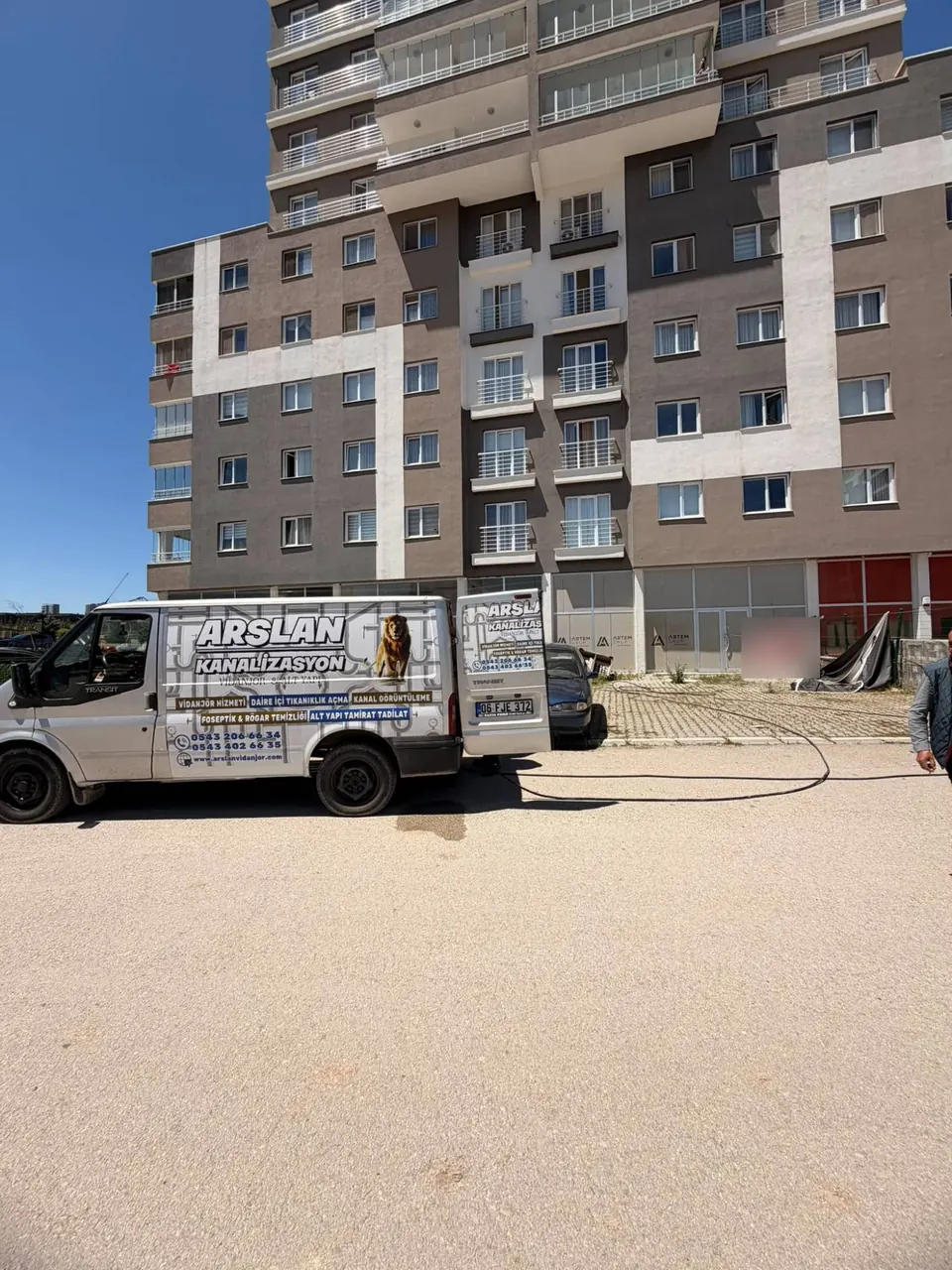 Yeni bir apartman önünde dükkân katına uzanan hortum hattı