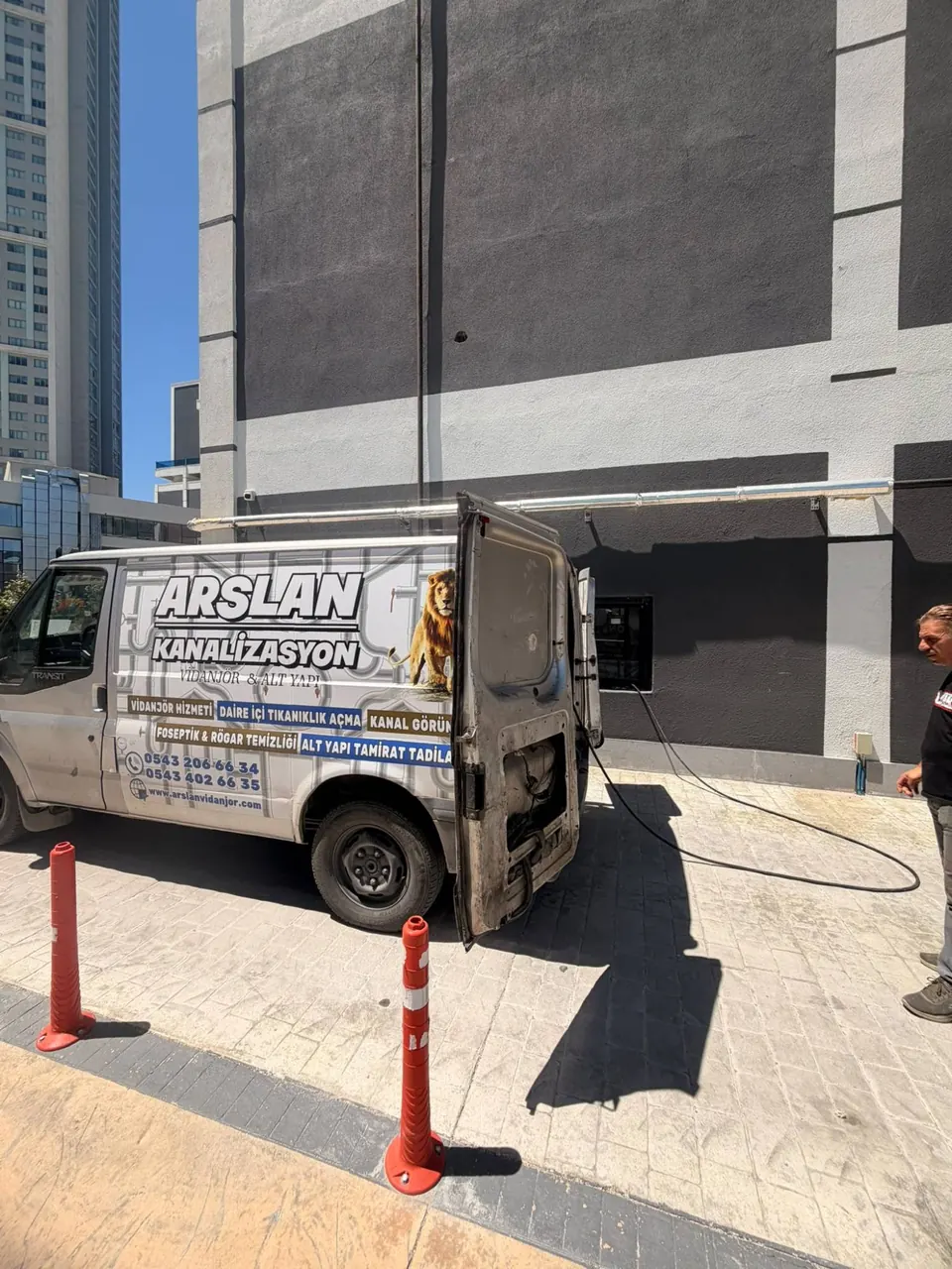 Bina cephesindeki bağlantıya uzanan hortum ve açık kapılı servis aracı