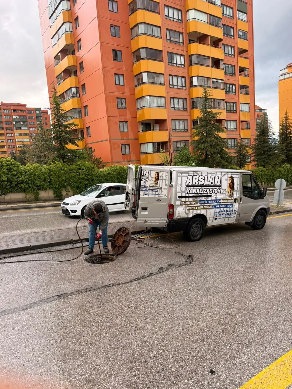 Cadde üzerindeki rögarda hortumla çalışan teknisyen