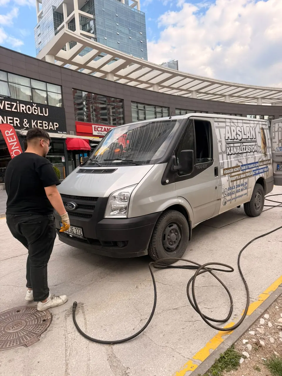 İş yerlerinin önündeki caddede rögar kapağı yanında hortum ve ekip