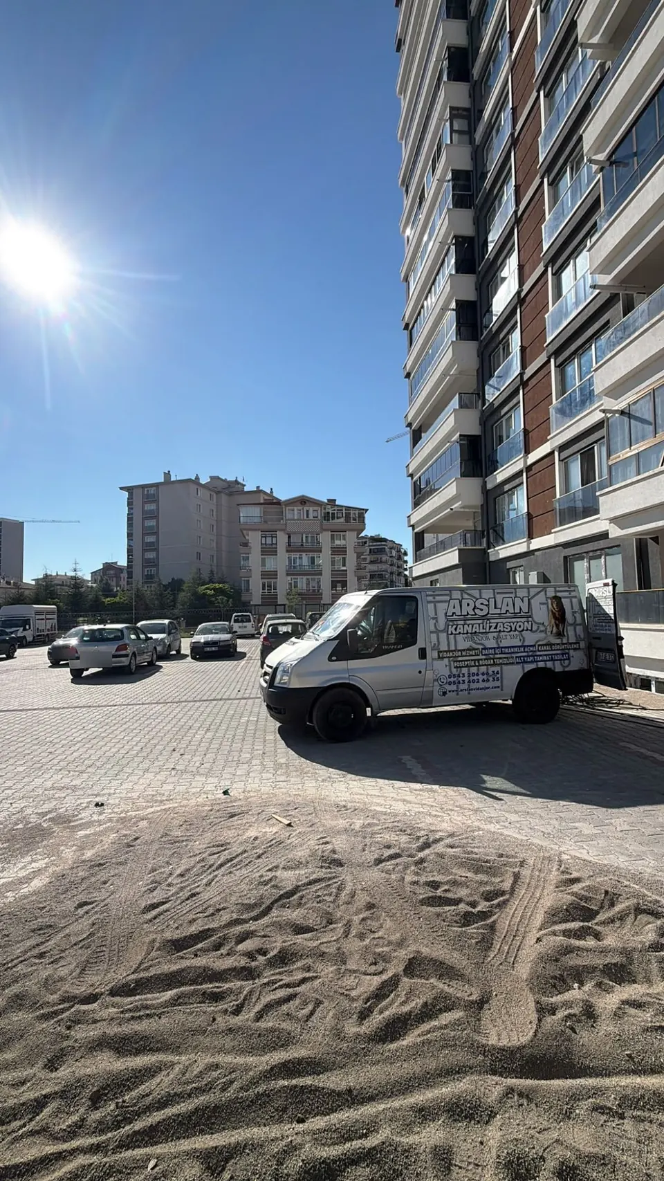 Yüksek bir konut bloğunun açık otoparkında servis aracı